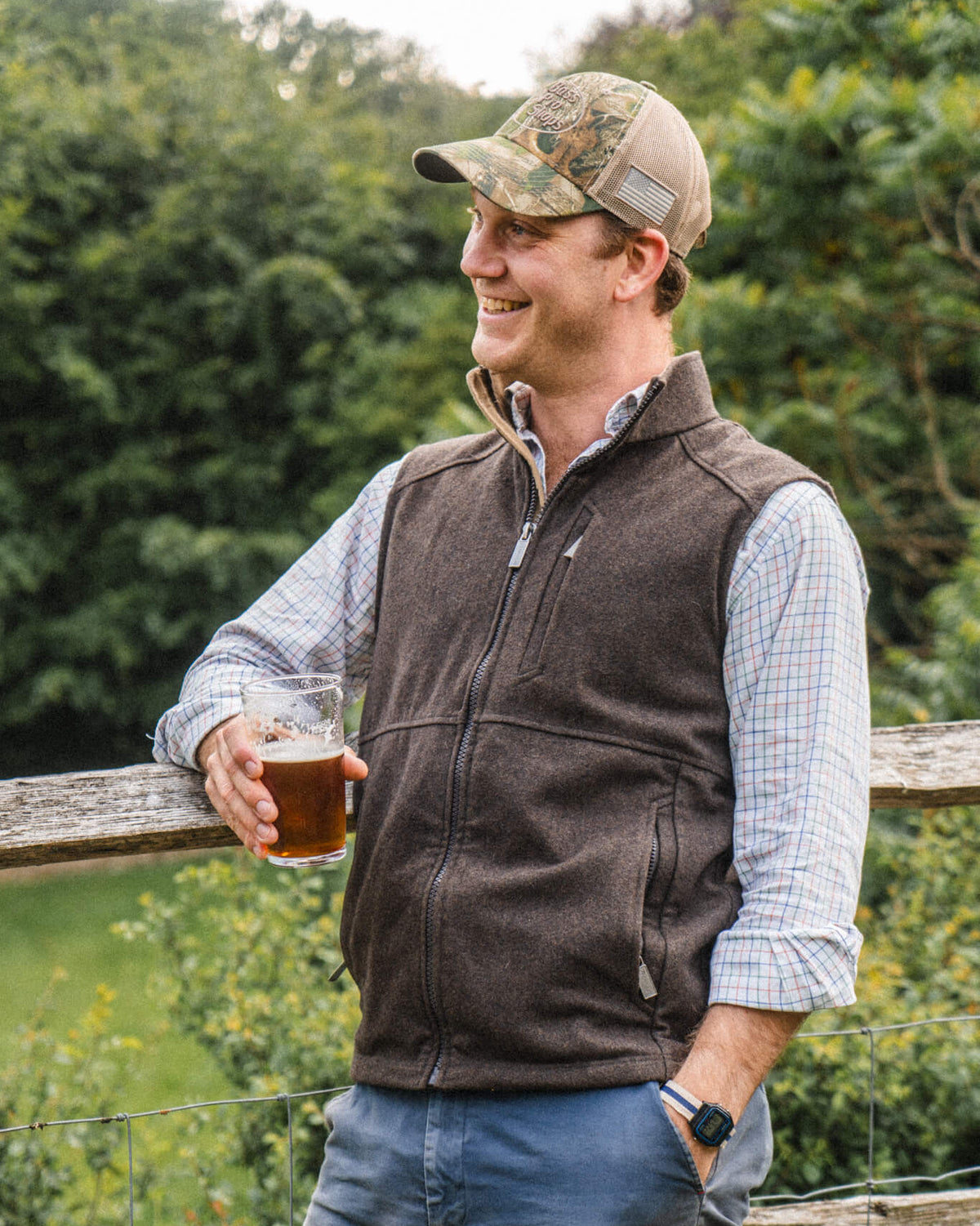 Man leaning on a fence wearing the Torr Wool gilet in Peat.