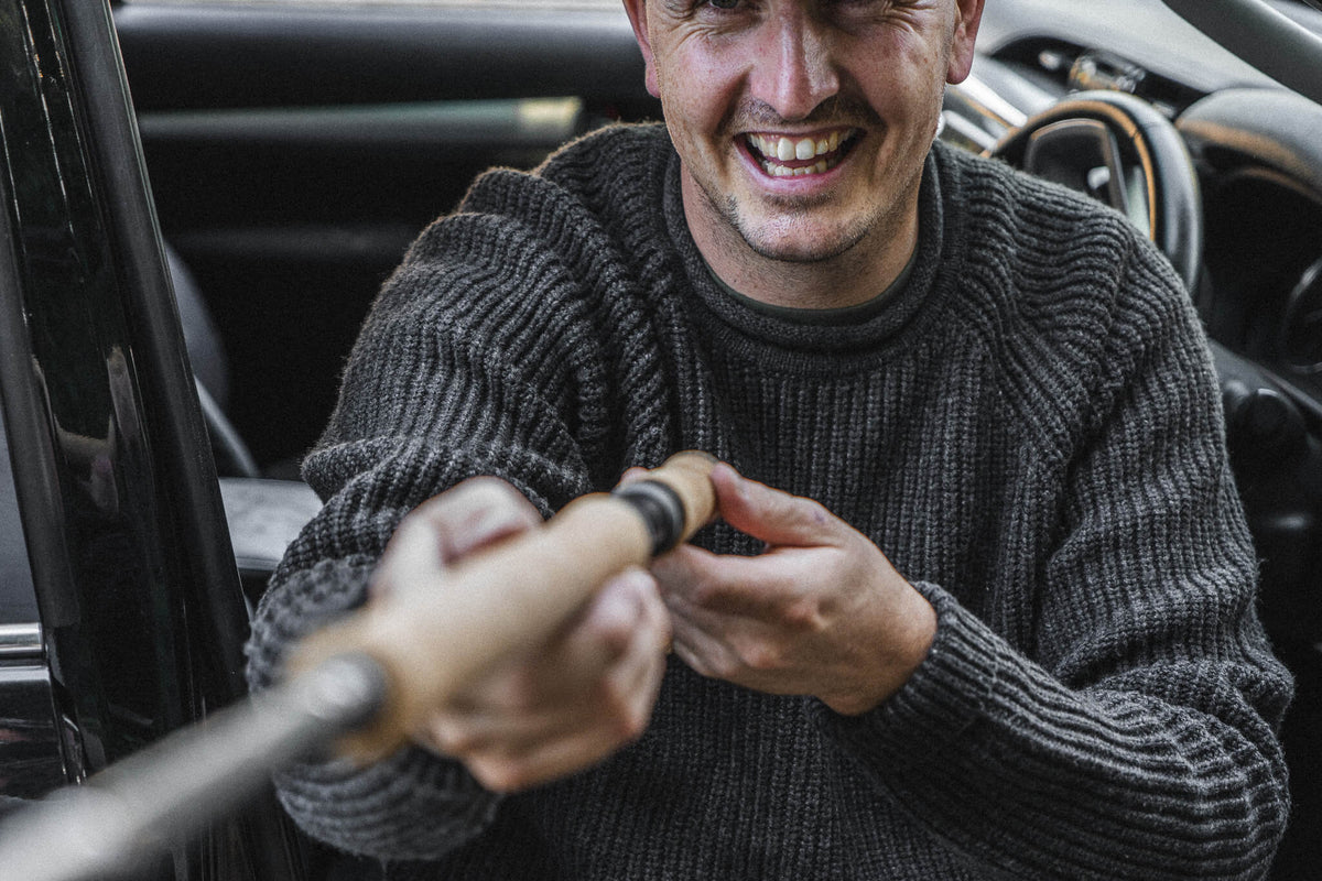 Tarbert Fisherman's Jumper in Slate, worn setting up a rod at the tailgate.