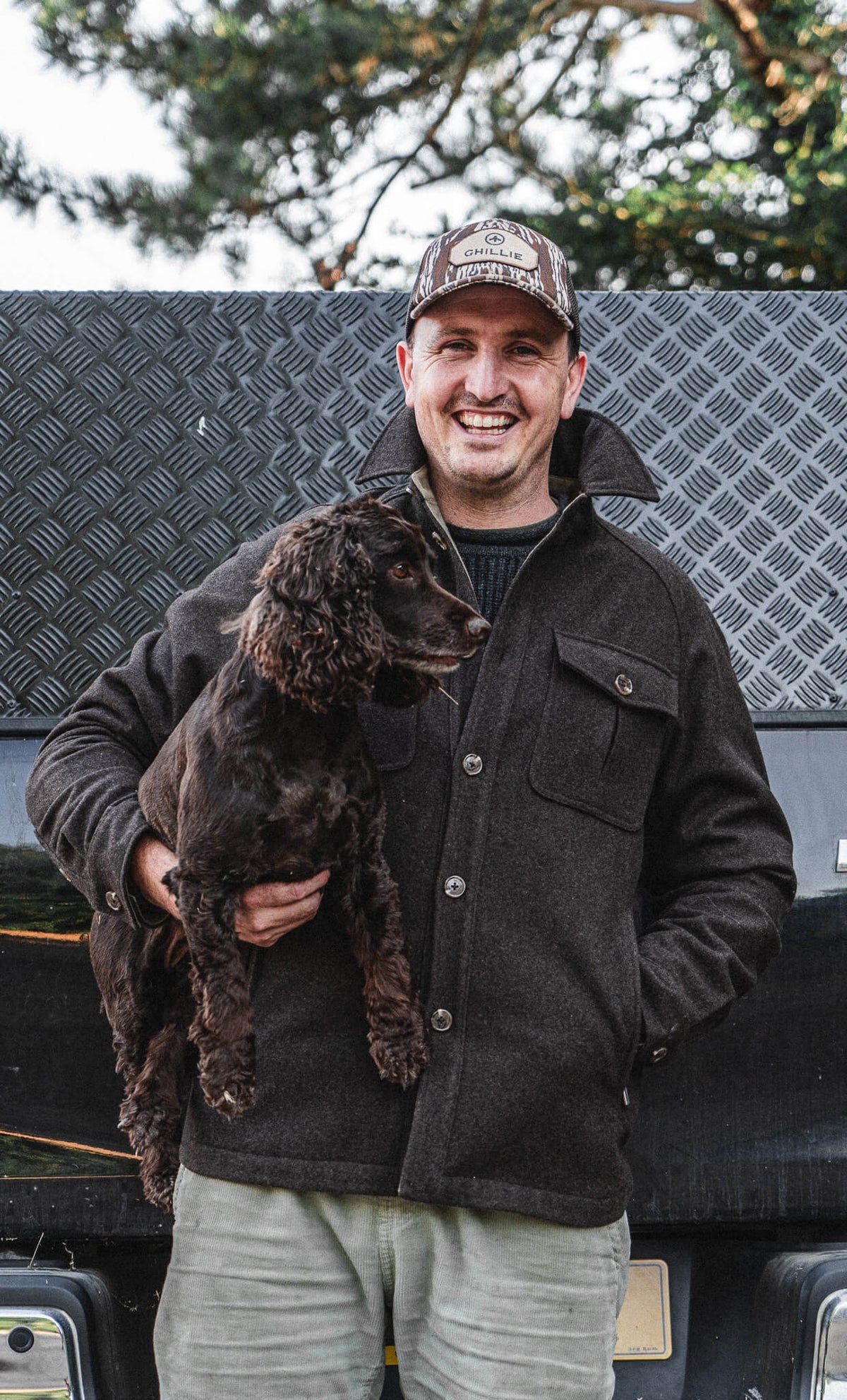 Arkle Wool Jacket, worn holding a spaniel at the back of a truck.