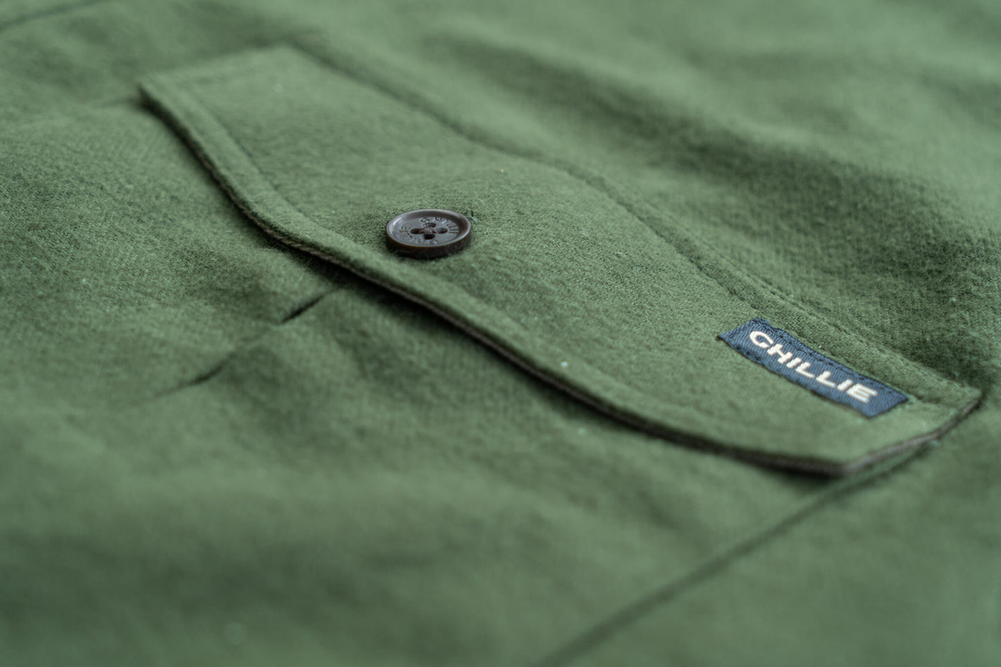 Close-up of a green fabric with a button and 'Ghillie' label.