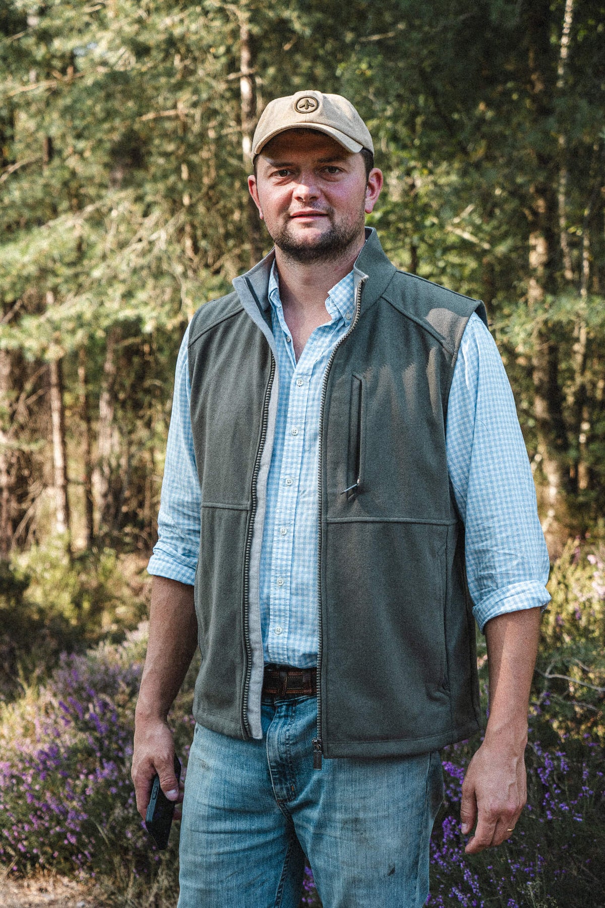 Torr Wool Gilet in Heather Green, worn open over a check shirt among the pines.