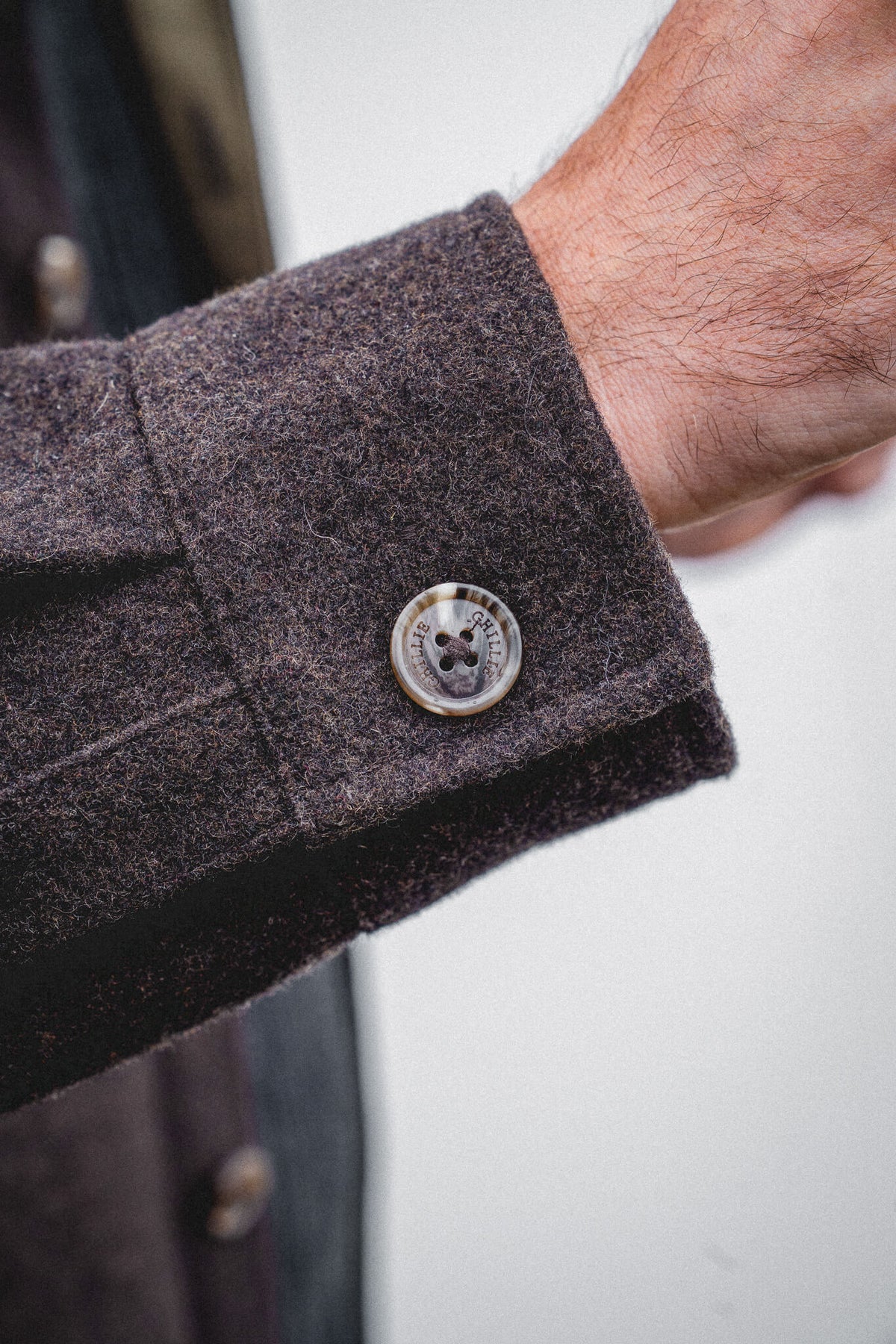 Arkle Wool Jacket, close view of the buttoned cuff and its engraved Ghillie button against the dark brown wool.